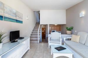 - un salon avec un canapé et une télévision dans l'établissement Apartamentos Punta Marina by LIVVO, à Morro del Jable
