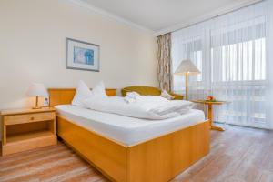 a bedroom with a large bed with white sheets at Hotel Bayerischer Hof in Bad Füssing