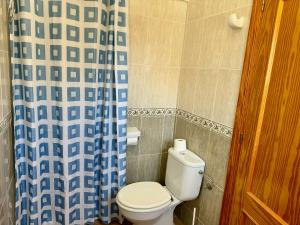 a bathroom with a toilet and a blue and white shower curtain at Adosado Ausias March in Els Poblets +2 photos