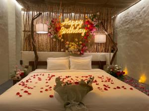 una camera da letto con un letto fiorito e un cartello di buon compleanno di Red Sands Pool Villa a Phan Thiet
