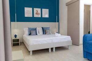 a bedroom with a white bed and a blue wall at Altavilla Boutique Holidays House in Marsala
