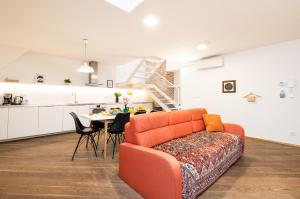 a living room with an orange couch and a kitchen at Rehorova apartments in Prague