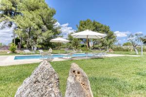 a large rock in the grass next to a pool at BioMasseria Santa Lucia in Alessano