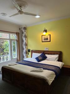 a bedroom with a large bed with a ceiling fan at Heritage Rose Inn in Srinagar