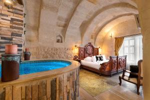 a bedroom with a large tub in a room with a bed at Elysion Cave Suites in Urgup