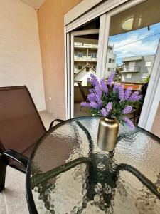 einen Glastisch mit einer Vase lila Blumen darauf in der Unterkunft Lajla Apartments in Dobra Voda + 25 Fotos