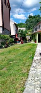 a grassy yard next to a building and a house at Historic Stone House KATI Perfect Family Retreat With Garden BBQ And Picturesque Landscapes in Ledenice