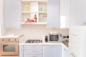 una cocina blanca con armarios y electrodomésticos blancos en Casa Alura, en Bérgamo