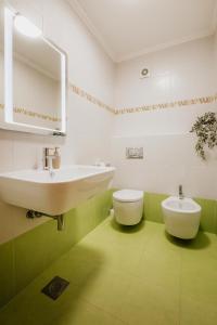 a green and white bathroom with a sink and a toilet at Supreme Apartment Bliss in Umag