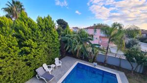 a swimming pool with two chairs and a building at Уютная вилла в Чамьюва in Kemer