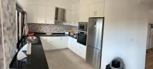 a kitchen with white cabinets and a stainless steel refrigerator at Cotovia Lodge in Sesimbra