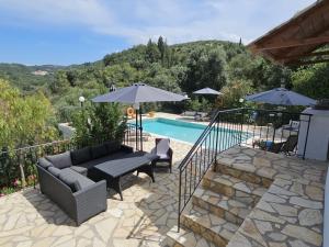阿查拉维Villa dionysus的一个带沙发和遮阳伞的庭院,毗邻一个游泳池
