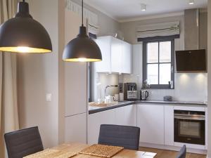 eine Küche mit weißen Schränken und einem Tisch und Stühlen in der Unterkunft Reetland am Meer - Ihre Superior Reetdachvilla E28 - Zwei Schlafzimmer, Kamin & pure Wohlfühlatmosphäre in Dranske