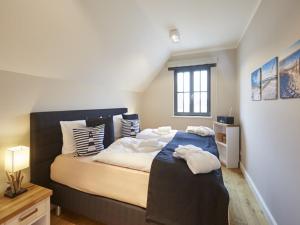 ein Schlafzimmer mit einem großen Bett und weißen Kissen in der Unterkunft Reetland am Meer - Ihre Superior Reetdachvilla E28 - Zwei Schlafzimmer, Kamin & pure Wohlfühlatmosphäre in Dranske + 10 Fotos