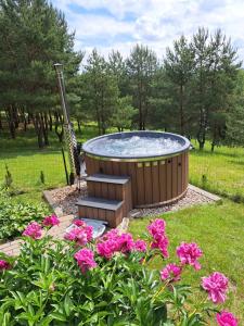 a hot tub in a garden with pink flowers at Sodyba Vilagio in Alanta