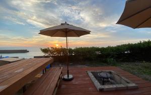 eine Terrasse mit einem Sonnenschirm und einer Bank mit einem Tisch in der Unterkunft Amami - Hotel - Vacation STAY 09731v in Amami