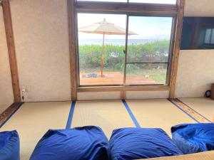 Zimmer mit blauen Kissen und einem Fenster mit Sonnenschirm in der Unterkunft Amami - Hotel - Vacation STAY 09731v in Amami