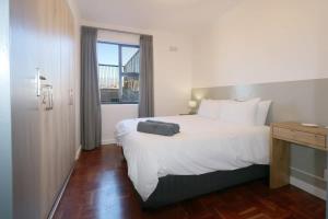 una habitación de hotel con una cama con una maleta. en South Surf Apartment, en Muizenberg