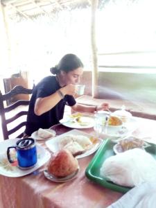 a woman sitting at a table with plates of food at Nirwana Resort in Habarana