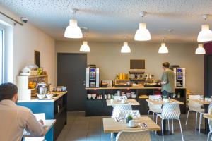 a restaurant with people preparing food in a kitchen at Nemea Appart Hotel Grand Cœur Nancy Centre in Nancy