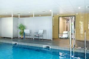 una piscina con 2 sillas y una mesa al lado en Nemea Appart Hotel Grand Cœur Nancy Centre en Nancy