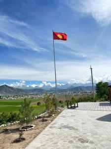 a red flag on a pole with mountains in the background at Eco Resort Kaiyrma in Bokonbayevo