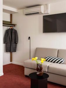 uma sala de estar com um sofá e uma televisão em Hôtel Dalila em Paris