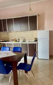 a kitchen with a table and blue chairs and a refrigerator at George’s Apartment in Orikum +10 photos