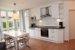 a kitchen with white cabinets and a table with chairs at Ebbe in Norden