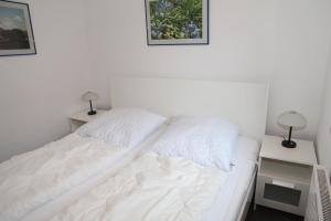 a white bed in a room with two night stands at Ebbe in Norden