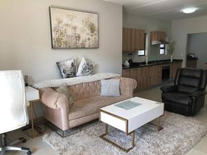 una sala de estar con un sofá y una silla en Exquisite Home In Sandton with Pool and Inverter, en Johannesburgo