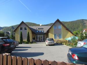 a house with cars parked in a parking lot at Penzion Raj in Rajecké Teplice