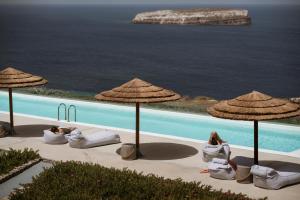 a group of people sitting under umbrellas next to a pool at Coco-Mat Hotel Santorini in Akrotiri