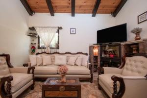 een woonkamer met banken en een flatscreen-tv bij Gioia Traditional House in Ágios Nikólaos