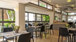 un ristorante con tavoli, sedie e finestre di Hotel Eiffel a Rimini