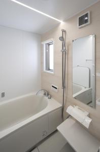 uma casa de banho branca com uma banheira e um espelho. em SEN.RETREAT CHIKATSUYU em Tanabe