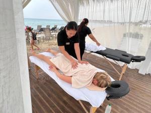 a woman getting a massage on a bed at the beach at Spacious Beachfront Two-Bedroom Apartment in Caesar Beach in Boghaz