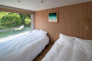 Duas camas brancas num quarto com uma janela em SEN.RETREAT CHIKATSUYU em Tanabe