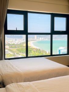 a bedroom with a large window with a view of the ocean at Tony Apartment -FLC Sea Tower Quy Nhon in Quy Nhon