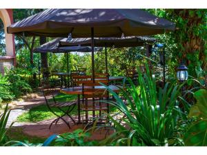 patio ze stołami i krzesłami pod parasolem w obiekcie Wigot Gardens Hotel w mieście Kisumu