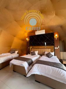 two beds in a room with a camp sign on the wall at Siwar Luxury Camp in Wadi Rum