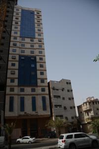 een hoog gebouw met auto's geparkeerd voor het bij Rakhaa Al Deafah Hotel in Mekka