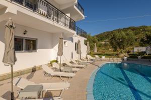 a pool with chairs and umbrellas next to a building at Denise Studios and Apartments in Argassi