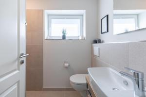 a white bathroom with a toilet and a sink at Hus Dree in Sankt Peter-Ording +13 photos