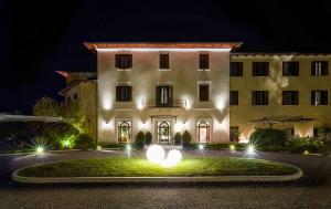 - un grand bâtiment blanc avec des lumières devant dans l'établissement San Giovanni Terme Rapolano, à Rapolano Terme
