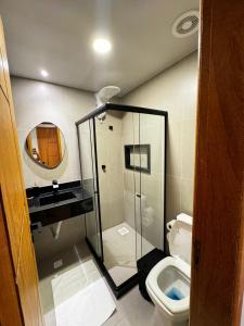 a bathroom with a toilet and a sink and a mirror at Suítes Viver Arraial do Cabo in Arraial do Cabo