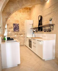 a kitchen with white appliances and a stone wall at Terrace Room on Parish Street in Luqa