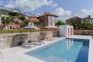 a pool with chairs and umbrellas next to a building at Feel Discovery Villa Aura Douro Valley in São Martinho de Mouros