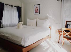a bed with white sheets and pillows in a room at TakFha Café & Resort in Ban Tha Ngam (1)