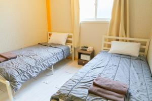 een kamer met 2 bedden en een raam bij Travelers A Korea Hostel in Seoul